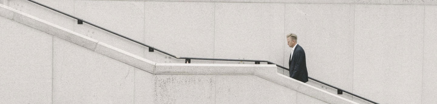A man climbing stairs that are placed on the side of a white building.
