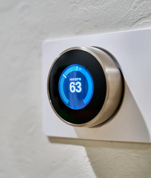 A digital thermometer placed on a wall showing the temperature inside of a house.